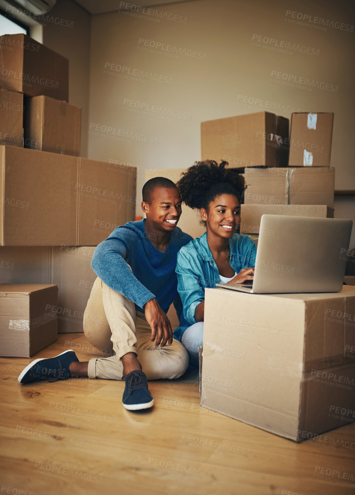 Buy stock photo Shot of a cheerful young couple browsing on a laptop together while being surrounded by cardboard boxes inside at home