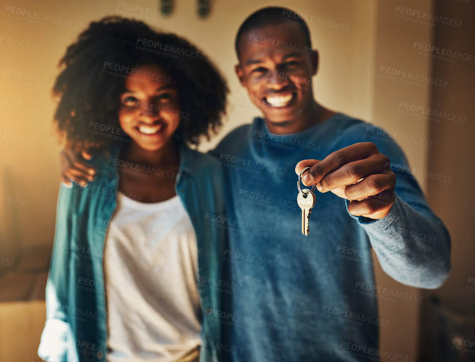 Buy stock photo Portrait of a cheerful young couple standing together while holding up a pair of keys to their new home