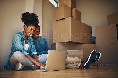 Buy stock photo Shot of a cheerful young couple browsing on a laptop together while being surrounded by cardboard boxes inside at home