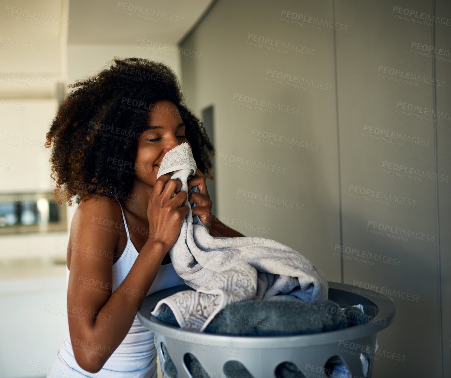 Buy stock photo Cropped shot of an attractive young woman smelling clean laundry at home