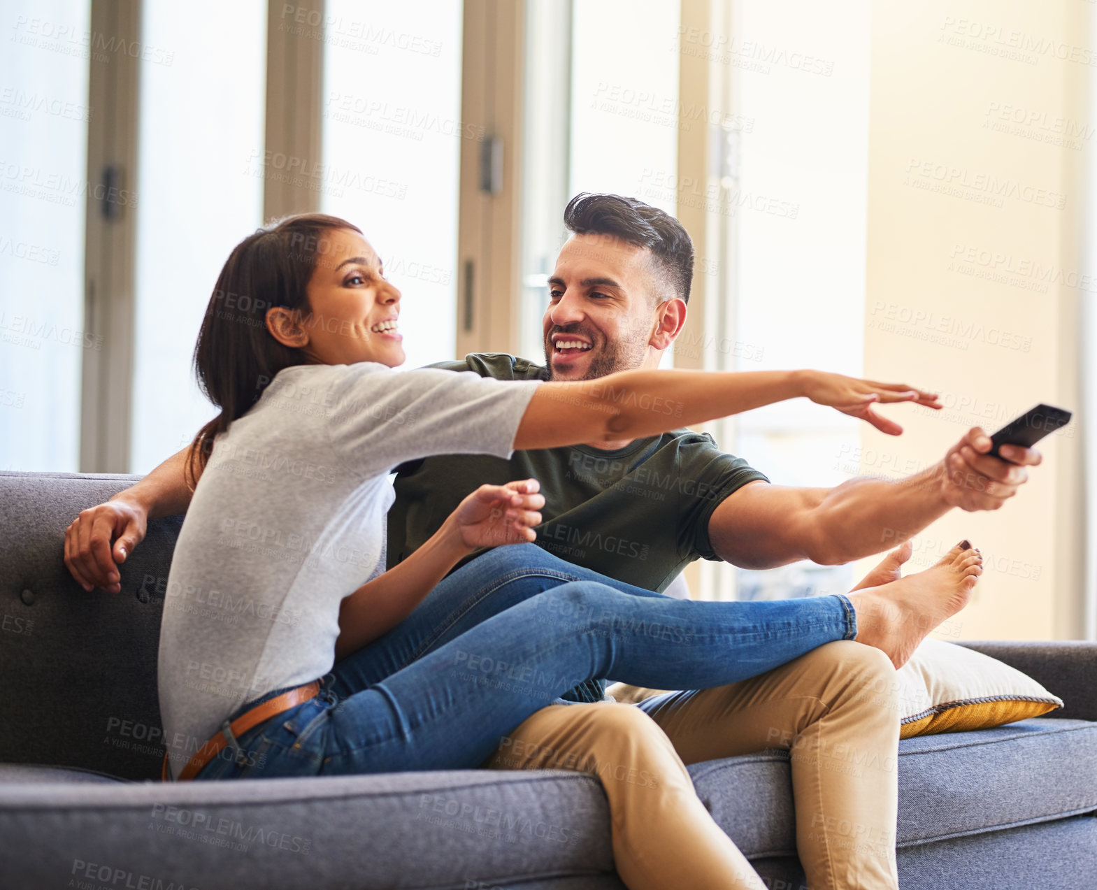 Buy stock photo Shot of a young couple fighting over the remote control while watching tv at home