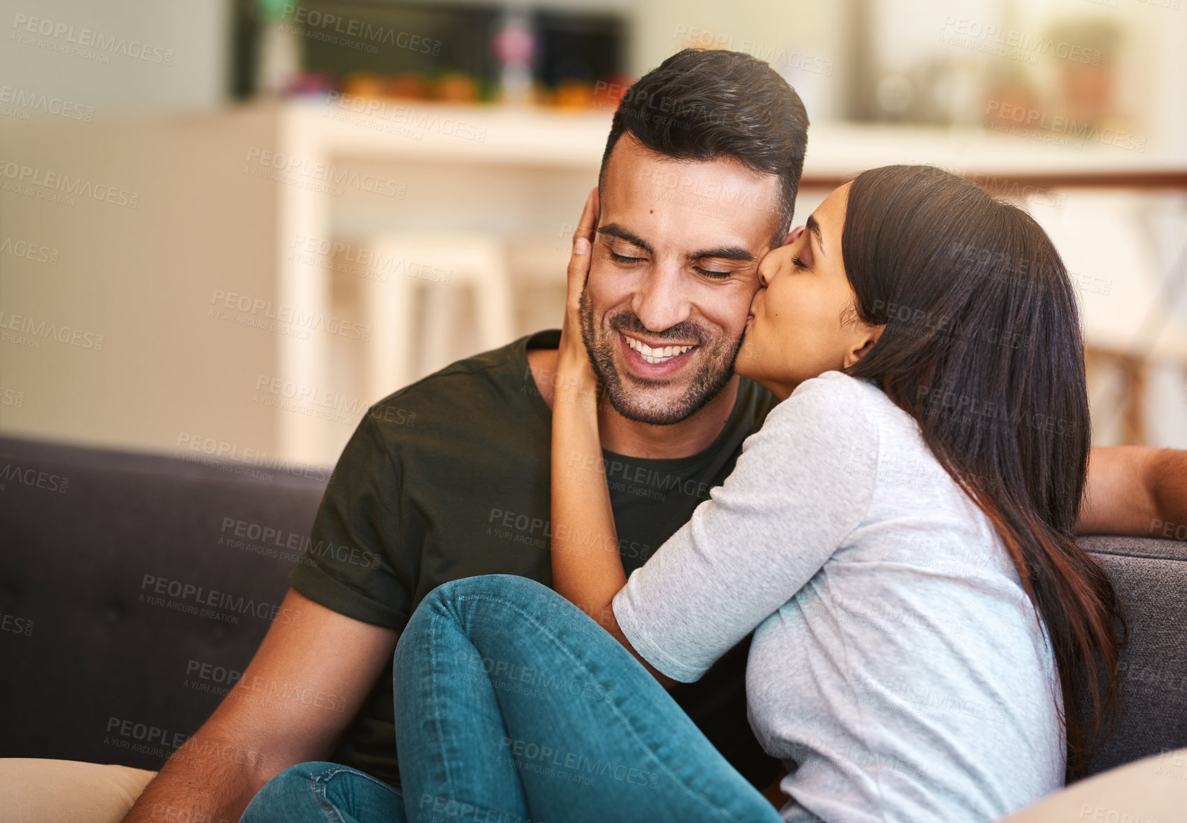 Buy stock photo Smile, couple and kiss on couch at house with love, bonding together and healthy relationship for security. Happy, people and affection with calm morning, romance and partner gratitude for commitment