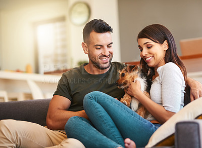 Buy stock photo Shot of an affectionate young couple relaxing with their pet dog at home