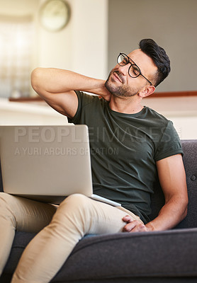 Buy stock photo Shot of a handsome young man suffering with neck pain while working on a laptop at home