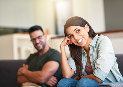 Buy stock photo Portrait of a young woman relaxing at home with her boyfriend in the background
