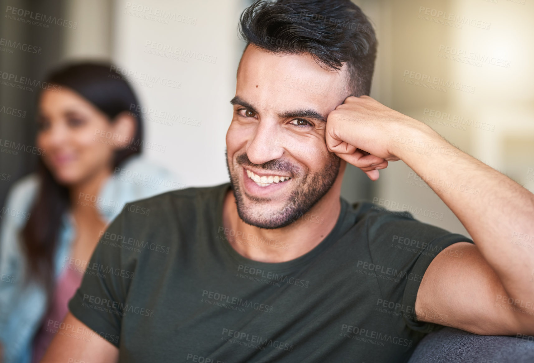 Buy stock photo Portrait of a young man relaxing at home with his girlfriend in the background