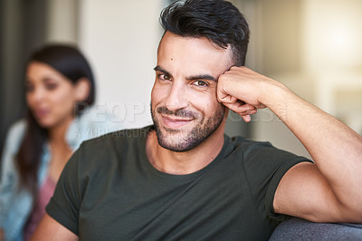 Buy stock photo Portrait of a young man relaxing at home with his girlfriend in the background