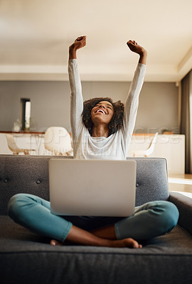 Buy stock photo Shot of an attractive young woman raising her arms while using a laptop at home