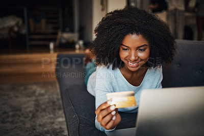 Buy stock photo Shot of an attractive young woman using a laptop and a credit card at home