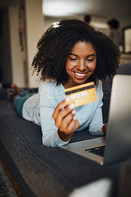 Buy stock photo Shot of an attractive young woman using a laptop and a credit card at home