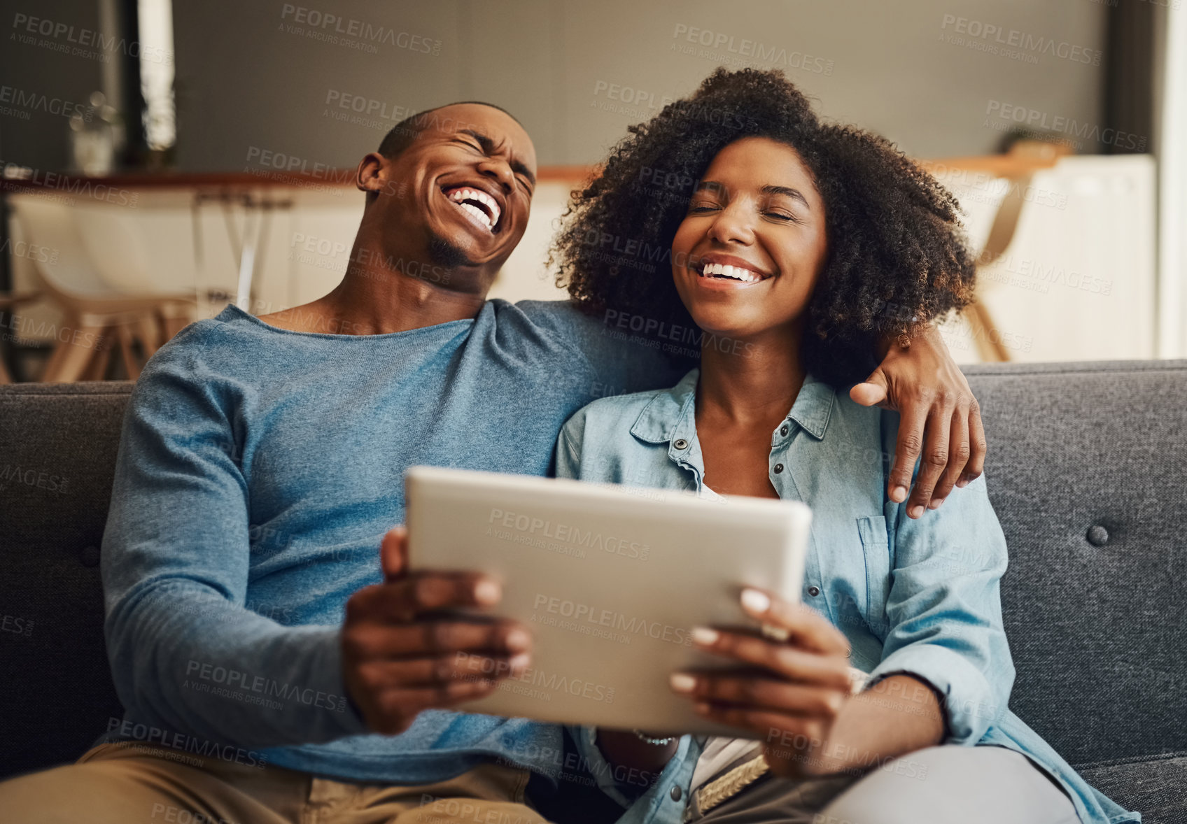 Buy stock photo Shot of a young couple laughing while using a digital tablet together at home