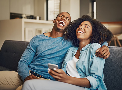 Buy stock photo Shot of a young couple laughing while using a cellphone together at home
