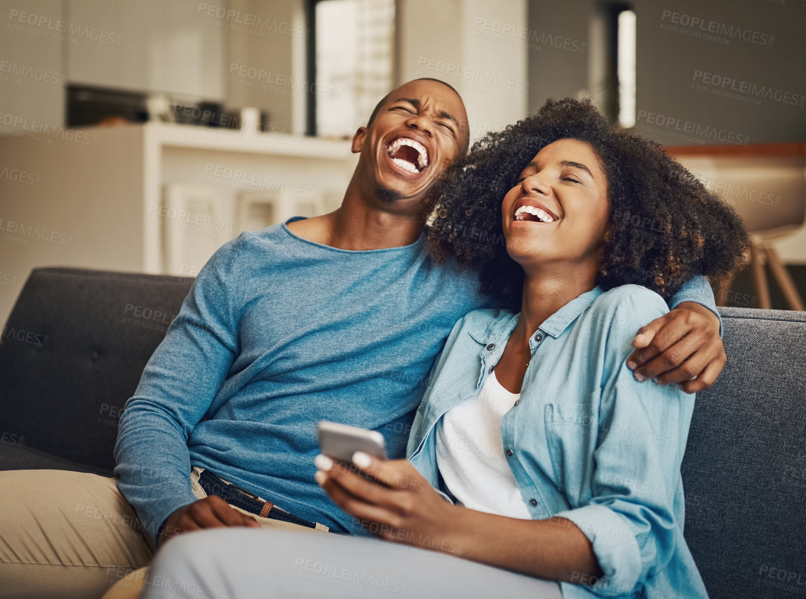 Buy stock photo Shot of a young couple laughing while using a cellphone together at home