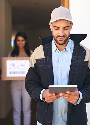 Buy stock photo Shot of a courier using a digital tablet while making a delivery to a customer