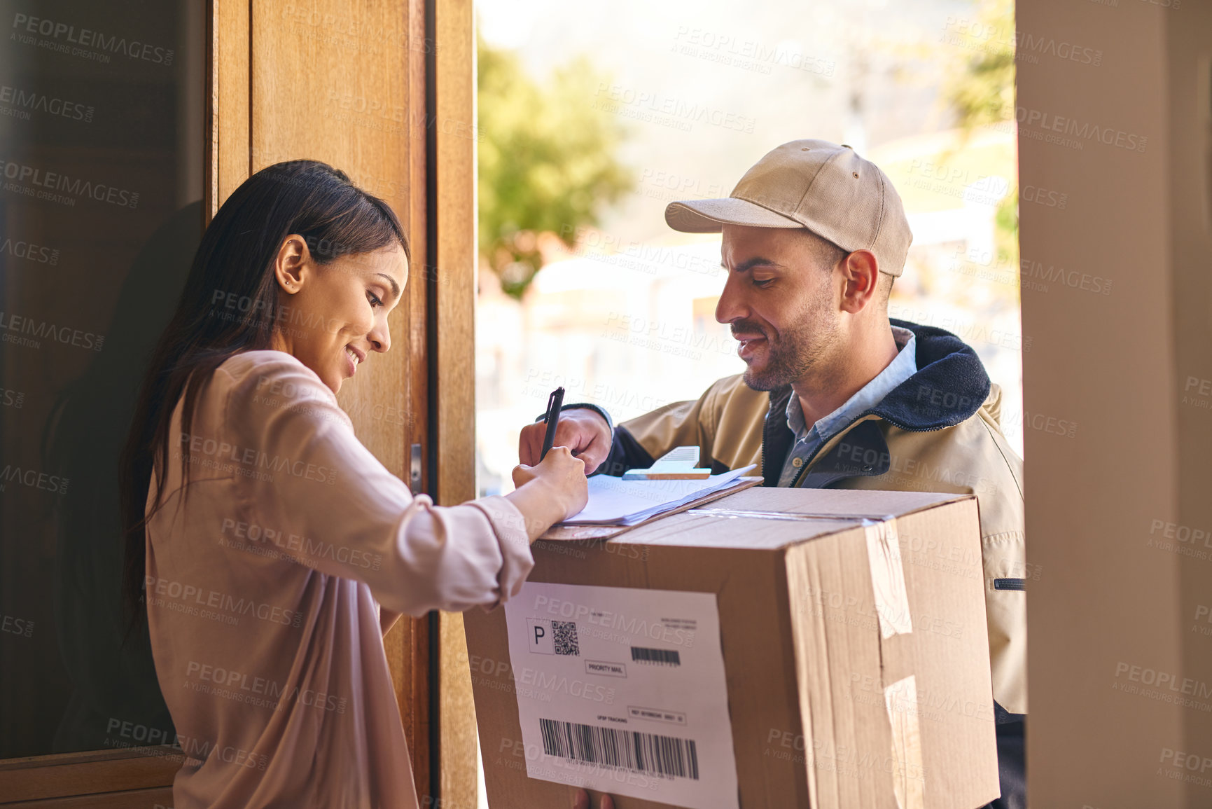 Buy stock photo Shot of a young woman signing for her delivery from the courier