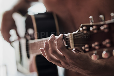 Buy stock photo Cropped shot of an unrecognizable man playing a guitar at home