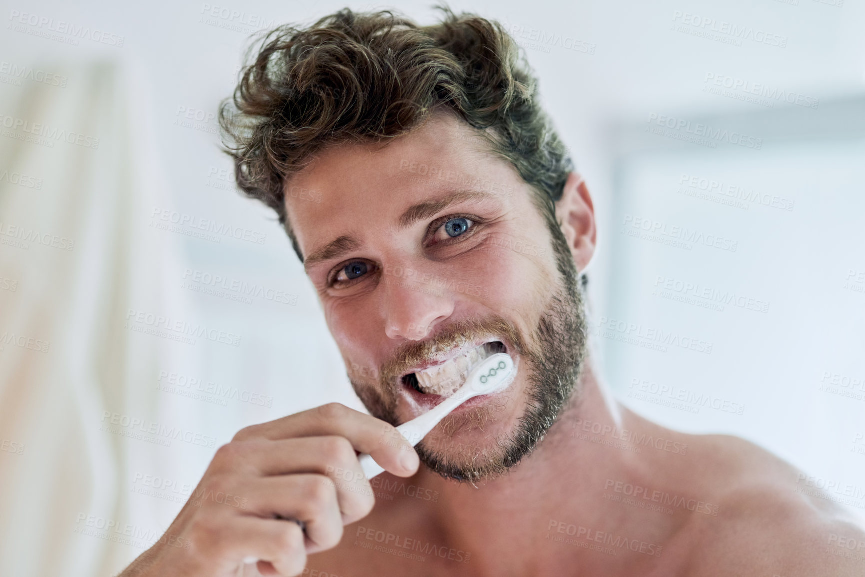 Buy stock photo Cropped shot of a handsome young man brushing his teeth at home