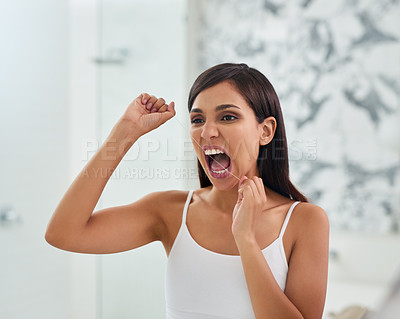 Buy stock photo Shot of an attractive young woman flossing her teeth in the bathroom