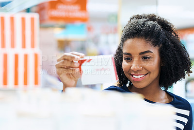 Buy stock photo Shot of a young woman looking at products in a pharmacy