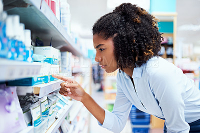 Buy stock photo Shot of a young woman looking at products in a pharmacy