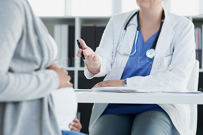 Buy stock photo Shot of an unrecognizable female doctor consulting with a pregnant patient at a hospital during the day