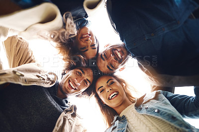 Buy stock photo Low angle portrait of a group of young friends huddled together while looking down at the camera outside during the day