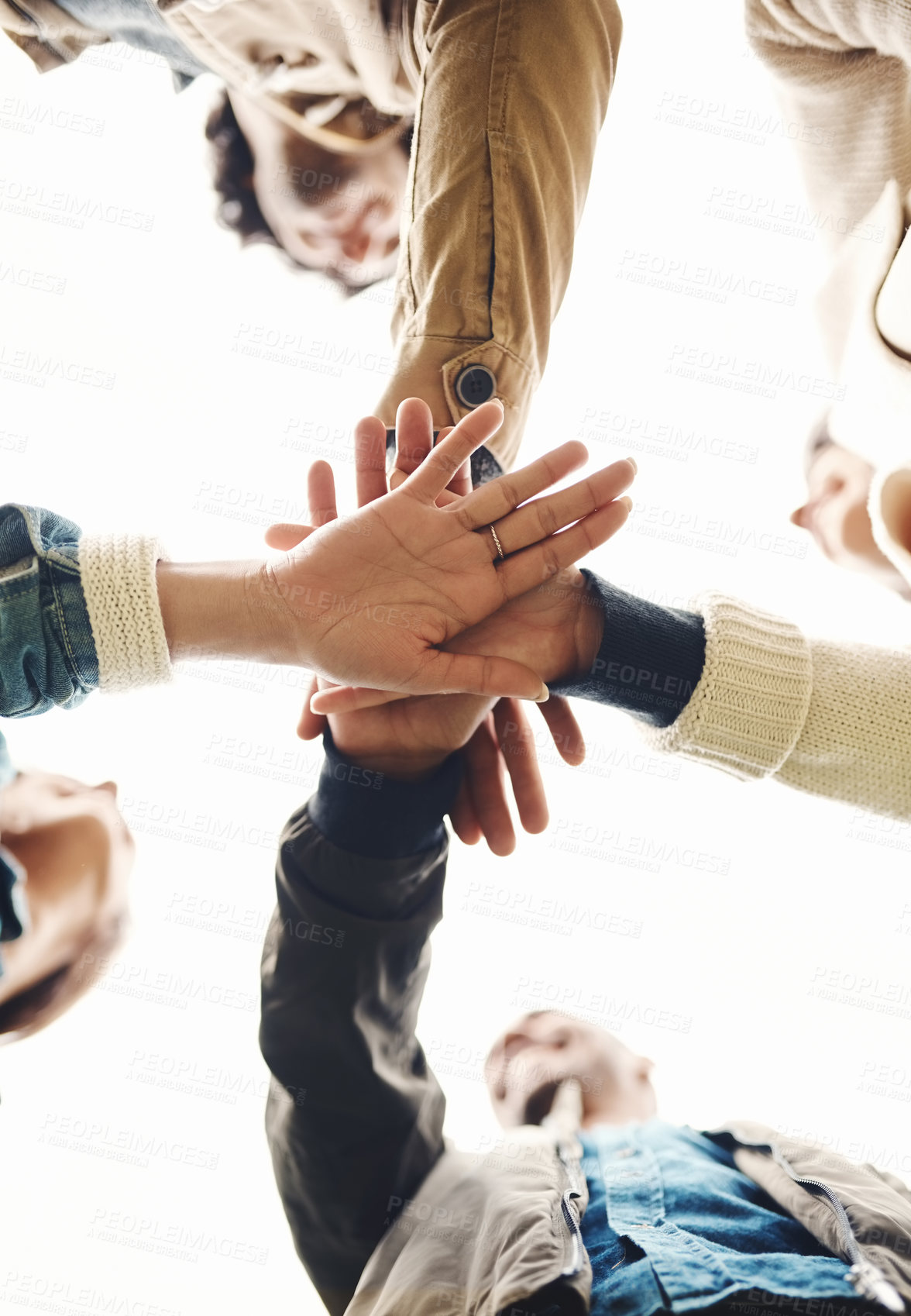 Buy stock photo Low angle shot of a group of young friends forming a huddle with their hands together outside during the day