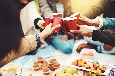 Buy stock photo Shot of a group of unrecognizable people celebrating with a celebratory toast at a picnic outside during the day