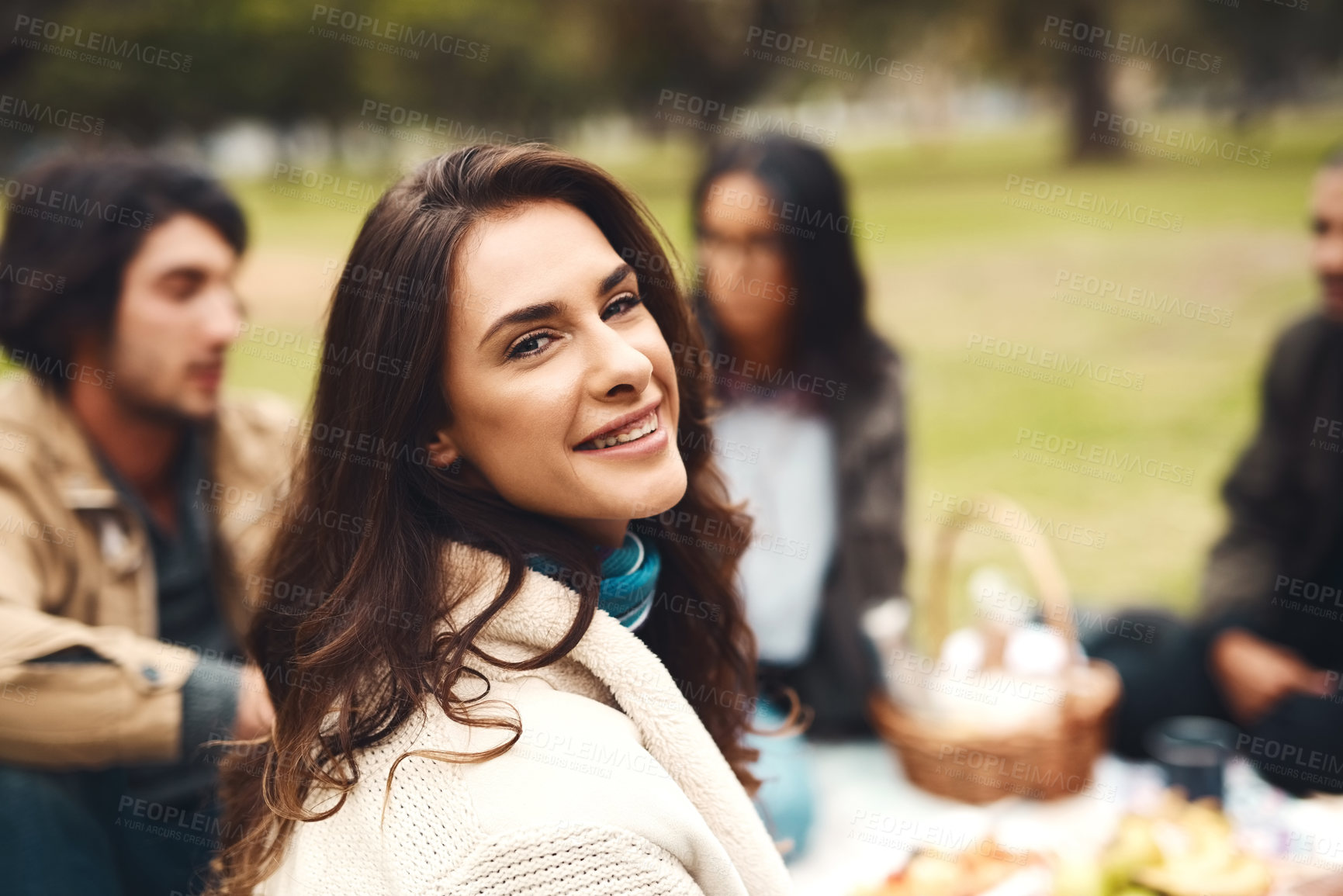 Buy stock photo Portrait of a cheerful young woman seated with his friends at a picnic outside during the day