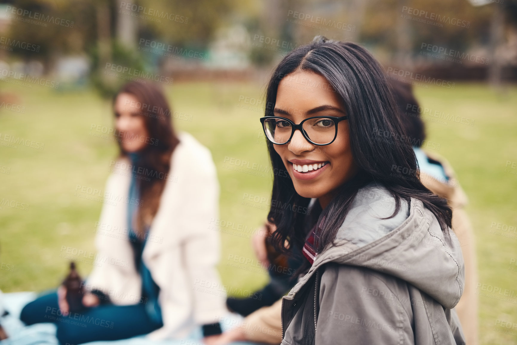 Buy stock photo Portrait of a cheerful young woman seated with his friends at a picnic outside during the day