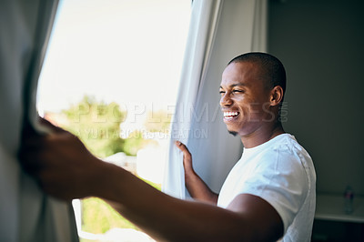 Buy stock photo Shot a handsome young man opening his bedroom curtains in the morning