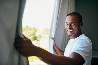 Buy stock photo Portrait of a handsome young man opening his bedroom curtains in the morning