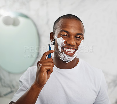 Buy stock photo Portrait of a handsome young man shaving his facial hair in the bathroom