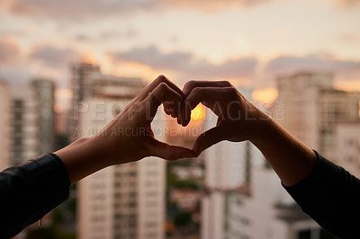 Buy stock photo Cropped shot of an unrecognizable couple making a heart shape with their hands against a city background