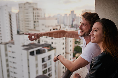 Buy stock photo Cropped shot of an attractive young couple on a rooftop looking over the city