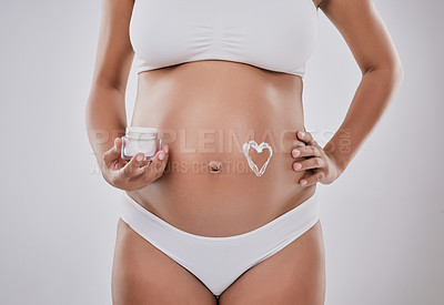 Buy stock photo Cropped studio shot of a pregnant woman with moisturizer in the shape of a heart on her belly