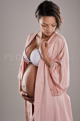 Buy stock photo Studio shot of a beautiful young pregnant woman wearing a robe and underwear against a gray background