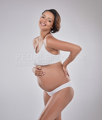 Buy stock photo Studio portrait of a beautiful young pregnant woman posing against a gray background