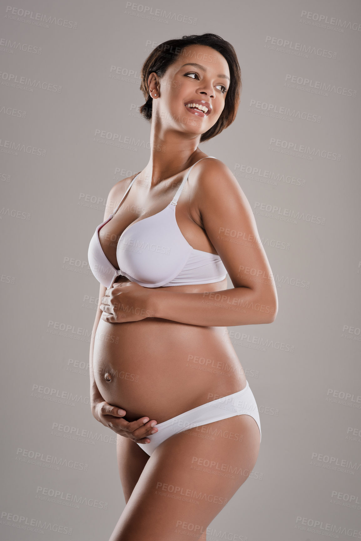 Buy stock photo Studio shot of a beautiful young pregnant woman posing in underwear against a gray background