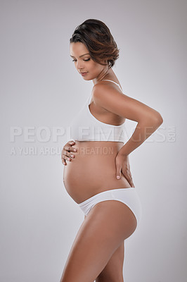 Buy stock photo Studio shot of a beautiful young pregnant woman posing against a gray background