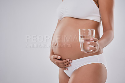 Buy stock photo Pregnancy, water and stomach of woman in studio for health, wellness and nutrition on white background. Pregnant, maternity and isolated person with glass for vitamins, nutrients and wellbeing