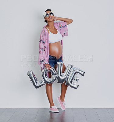 Buy stock photo Studio shot of a beautiful young pregnant woman holding up a word balloon that reads 'love' against a gray background