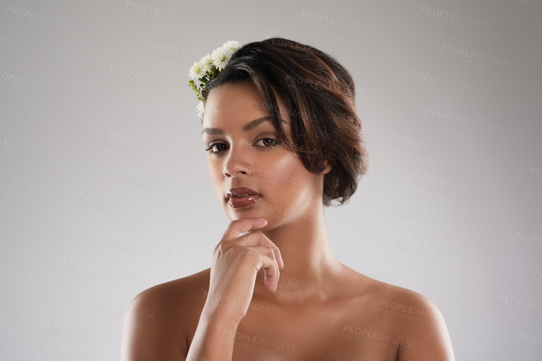Buy stock photo Studio portrait of a beautiful young woman with flowers in her hair posing against a gray background