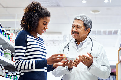 Buy stock photo Shot of a pharmacist assisting a young woman in a chemist