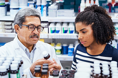 Buy stock photo Shot of a pharmacist assisting a young woman in a chemist