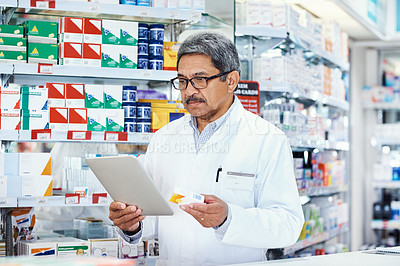 Buy stock photo Shot of a mature pharmacist using a digital tablet in a chemist