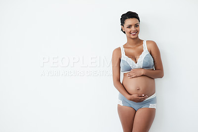 Buy stock photo Studio portrait of a pregnant young woman standing against a white background