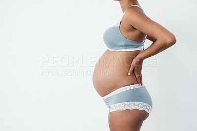 Buy stock photo Studio shot of a pregnant young woman experiencing back pain while standing against a white background