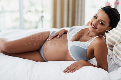 Buy stock photo Portrait of a pregnant young woman relaxing on her bed at home