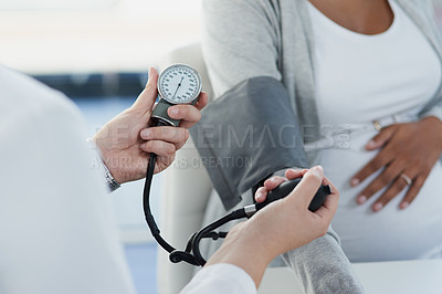 Buy stock photo Shot of an unrecognizable female doctor checking the blood pressure of a pregnant patient at a hospital during the day